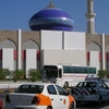 An Orange And White Taxi In Front Of A Mosque In Ruwi